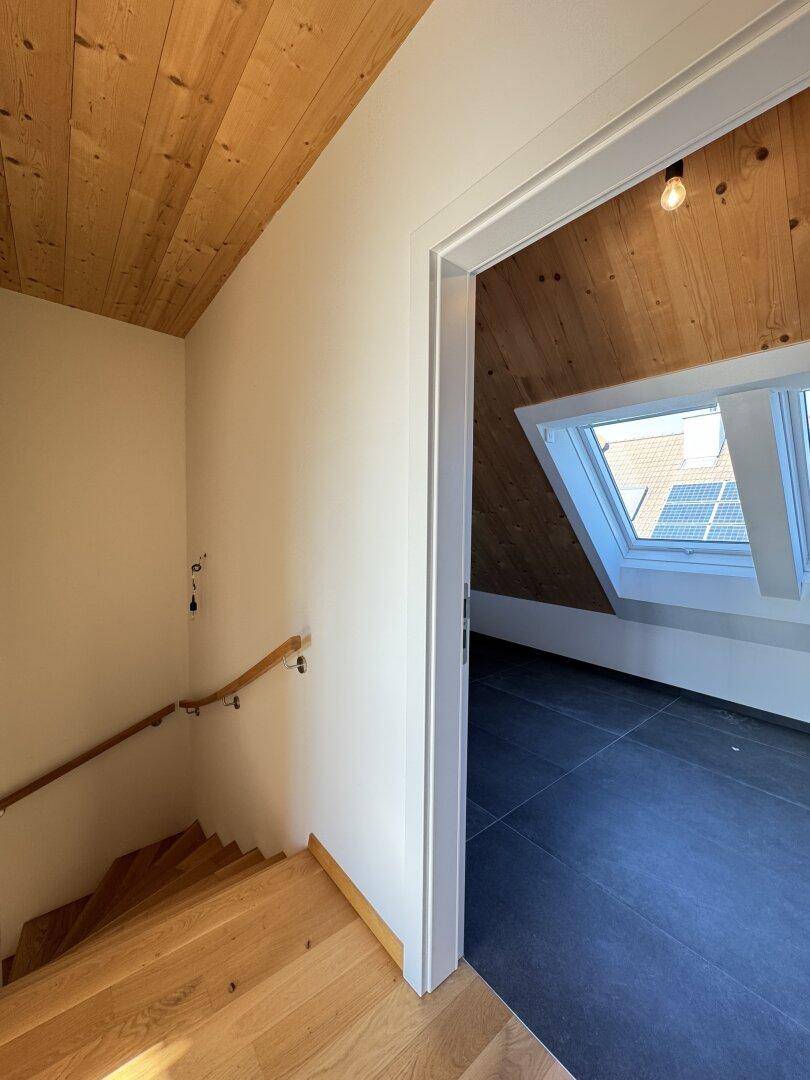 Treppenaufgang mit Zugang zu einem Badezimmer mit Dachfenstern und Solaranlage im Hintergrund.