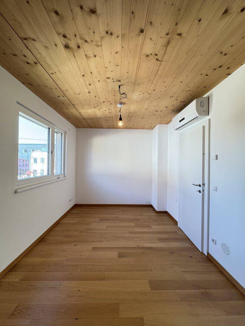 Gemütliches Schlafzimmer mit Holzbalkendecke, Parkettboden und Klimaanlage für Komfort.