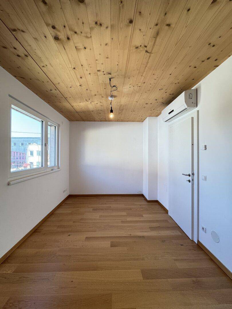 Komfortables Schlafzimmer mit Holzbalkendecke, Parkettboden und Klimaanlage, viel Tageslicht.