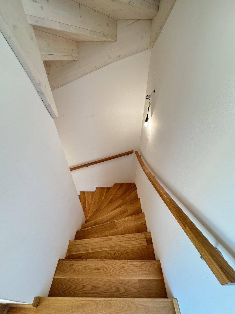 Elegante Holztreppe mit hellem Geländer, verbindet die verschiedenen Wohnebenen.