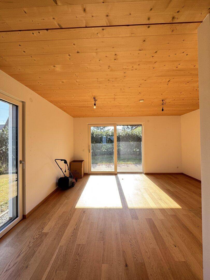 Heller Wohnraum mit Holzbalkendecke, Parkettboden und direktem Zugang zum Garten.