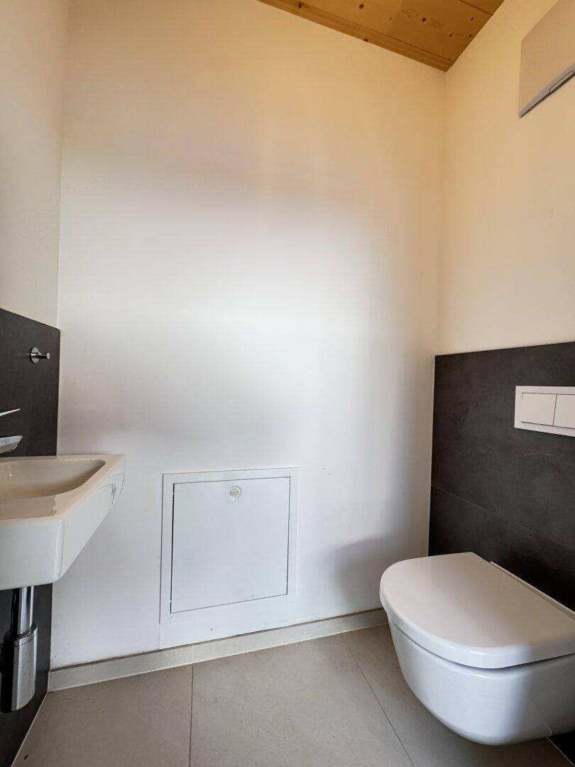 Funktionelles Gäste-WC mit wandhängendem WC und kleinem Waschbecken, in modernem Design.