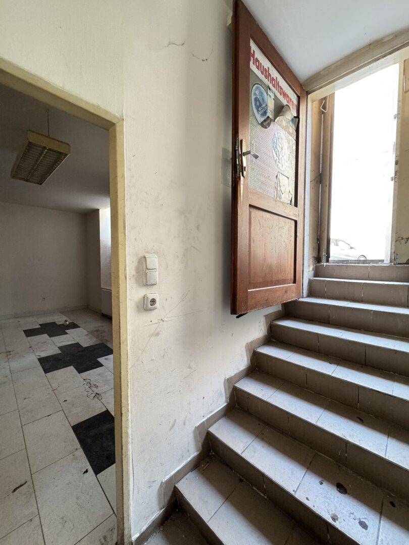 Treppenhaus mit Stufen, die nach oben führen, und einer offenen Tür zu einem angrenzenden Raum.