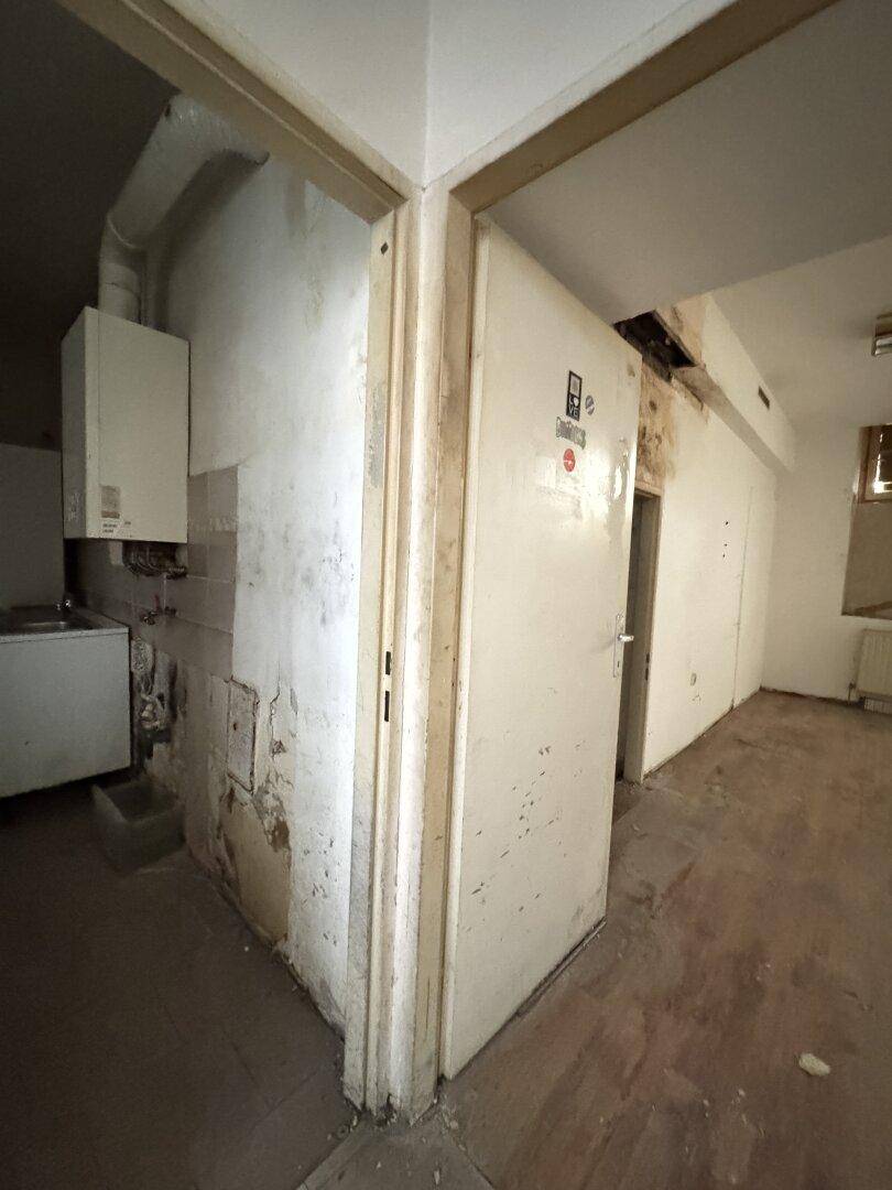 Ecke eines Raumes mit einem Warmwasserbereiter an der Wand und einem Waschbecken, deutet auf einen Hauswirtschaftsraum hin.