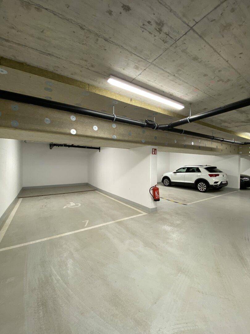 Tiefgaragenstellplatz mit einem geparkten Auto und Feuerlöscher an der Wand.