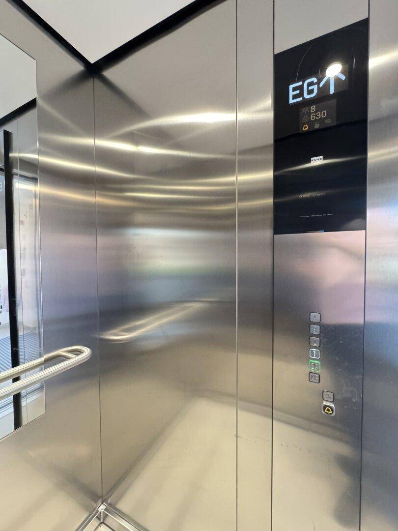 Moderner Aufzug mit Edelstahloberflächen und digitaler Etagenanzeige.