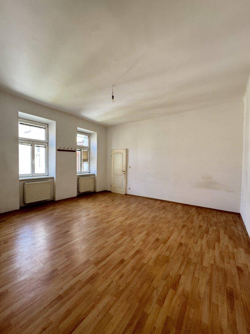Leerer Raum mit Holzboden und weißen Wänden, der auf eine Renovierung wartet.