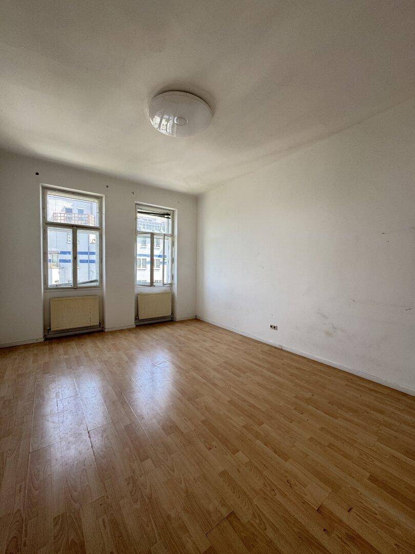 Geräumiges Zimmer mit Holzboden und viel Tageslicht, ideal für Wohn- oder Schlafbereich.