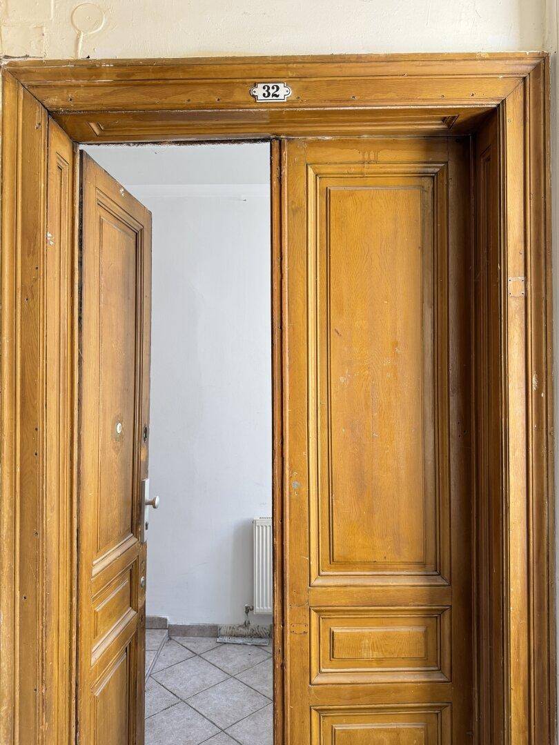 Offene Holztür mit der Nummer 32, die einen Blick in den gefliesten Flur freigibt.