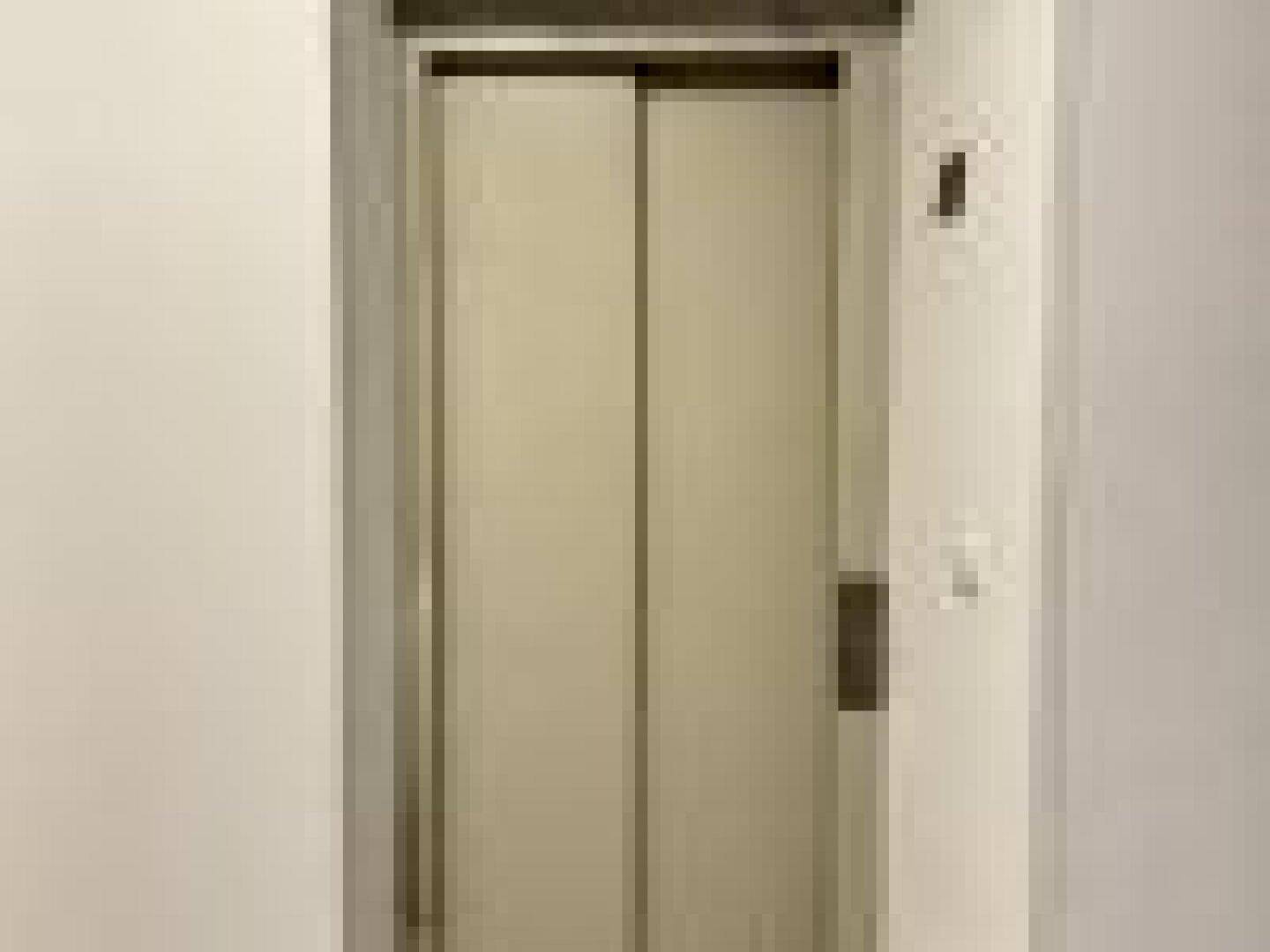 Geschlossene Aufzugtür in einem hellen Flur, bereit zur Benutzung.