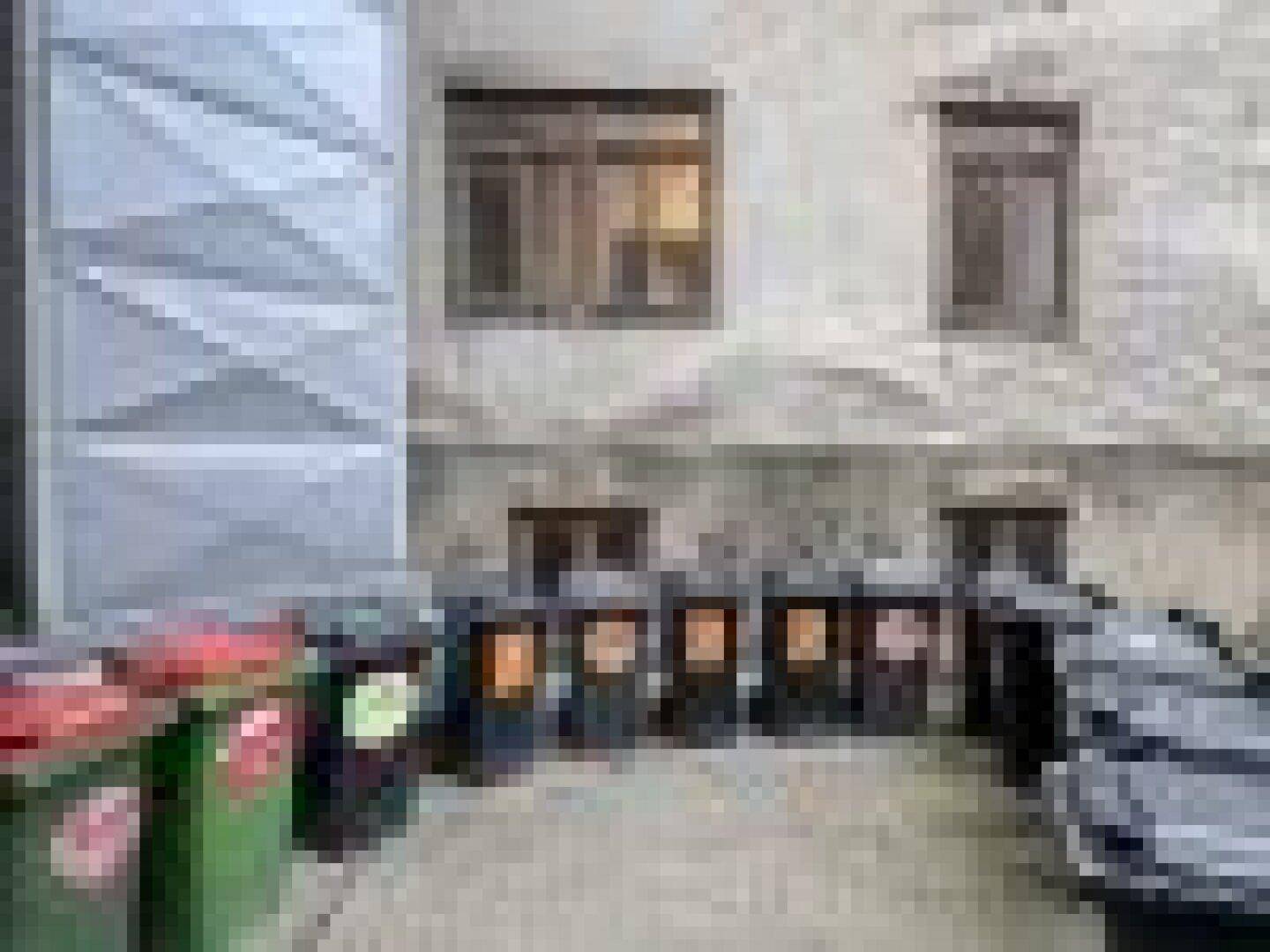 Hinterhofbereich eines Gebäudes mit Mülltonnen und einer unscheinbaren Fassade.