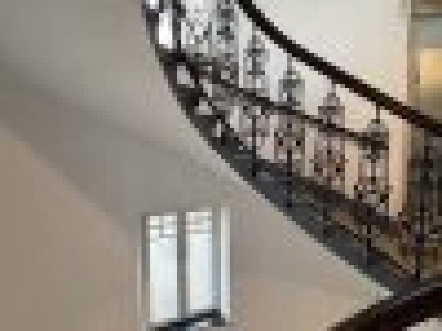 Elegantes Treppenhaus mit geschwungenem Geländer und einem Fenster, das Licht spendet.
