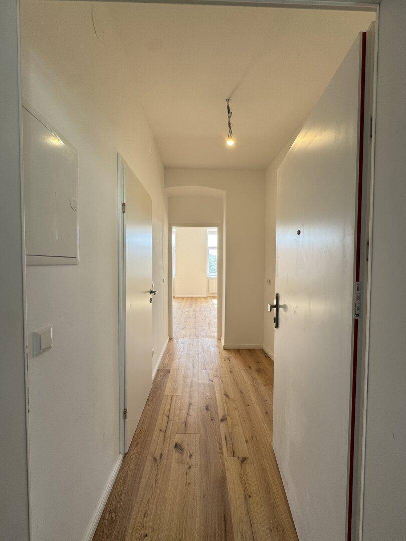 Heller Flur mit Holzboden und mehreren Türen, der den Zugang zu weiteren Räumen ermöglicht.