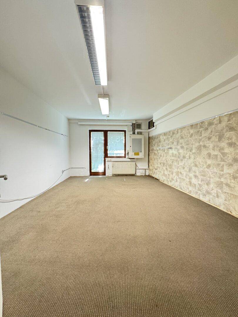 Geräumiger Raum mit Teppichboden und einer Tür zum Außenbereich, ideal für Büronutzung.