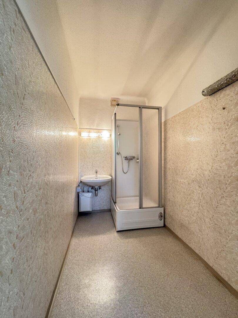 Kleines Badezimmer mit Duschkabine und Waschbecken, das eine Modernisierung benötigt.