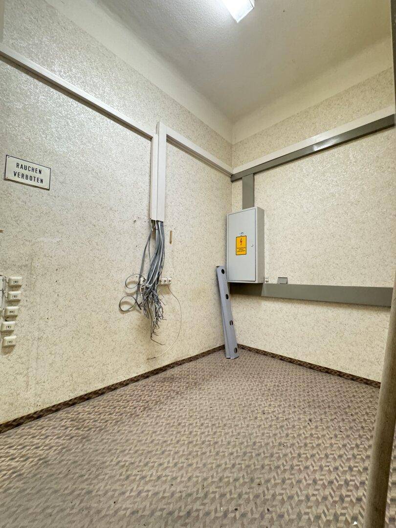 Kleiner Raum mit elektrischem Schaltkasten und sichtbaren Kabeln, ideal als Technikraum.