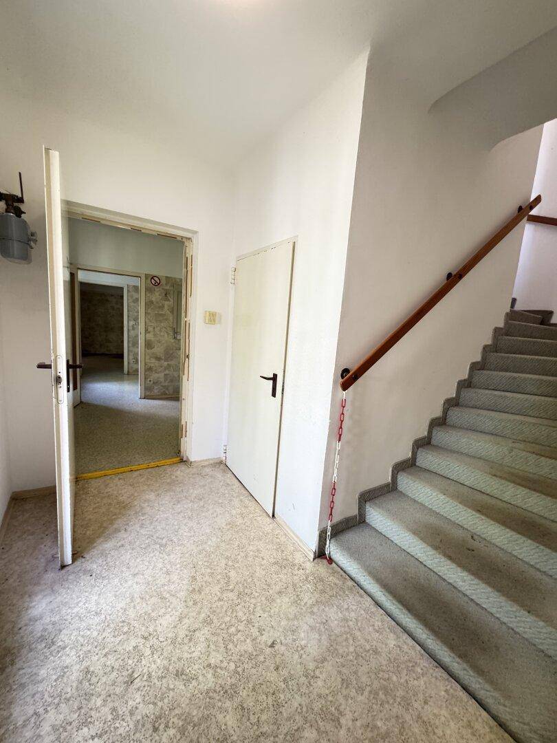 Treppenhaus mit Steinstufen und Holzgeländer, das zu den oberen Etagen führt.