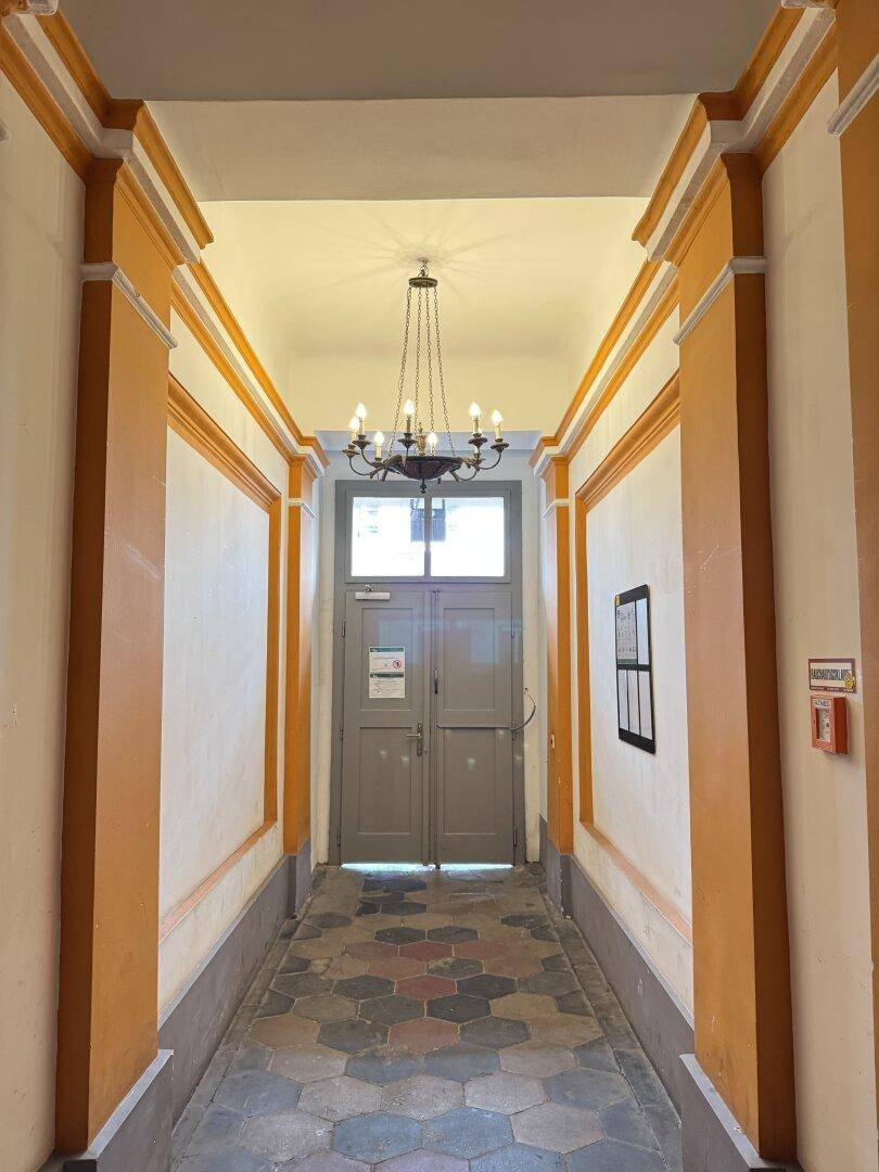 Eleganter Hausflur mit dekorativen Elementen, Kronleuchter und Zugang zum Gebäude.