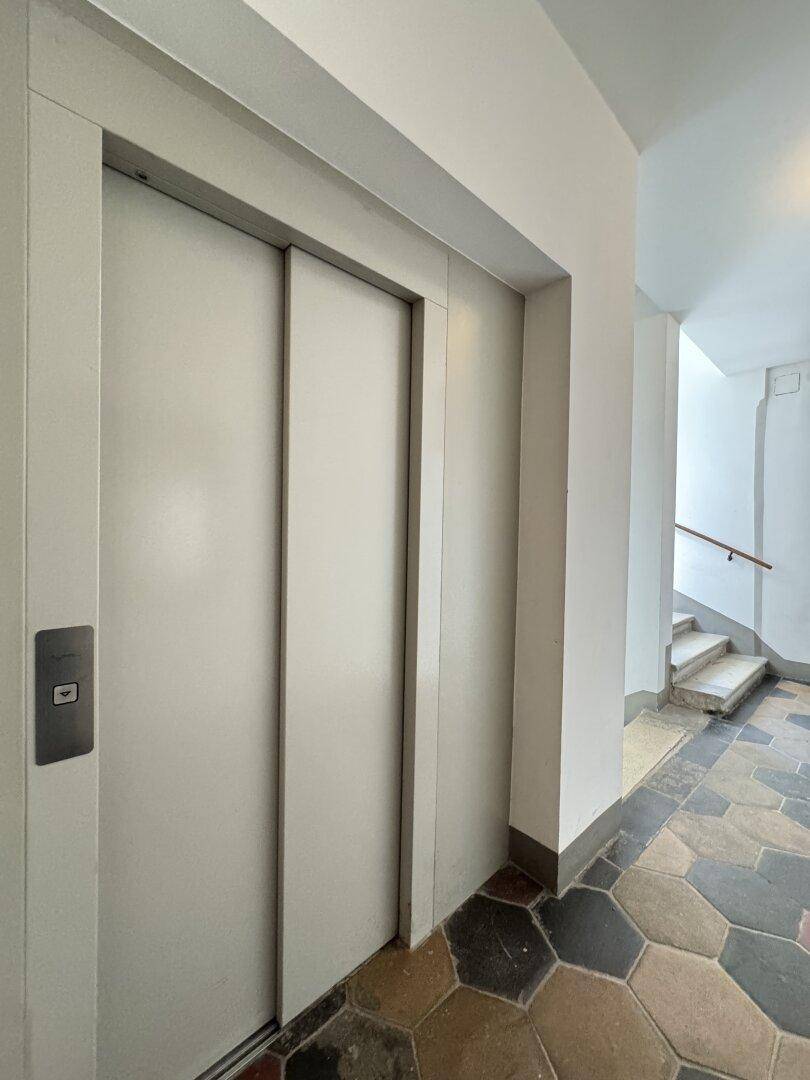 Moderner Aufzug im Eingangsbereich des Gebäudes, neben dem Treppenhaus gelegen.
