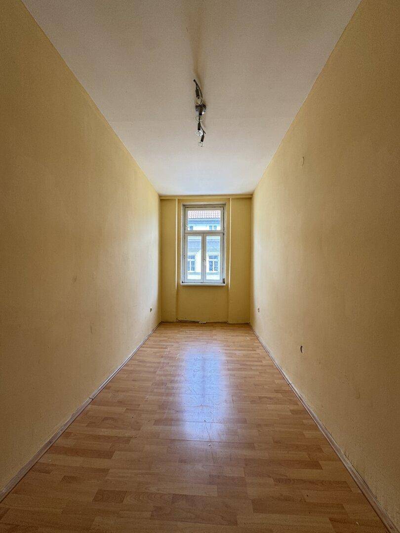 Leerer Raum mit Laminatboden und gelben Wänden, bereit zur individuellen Gestaltung.
