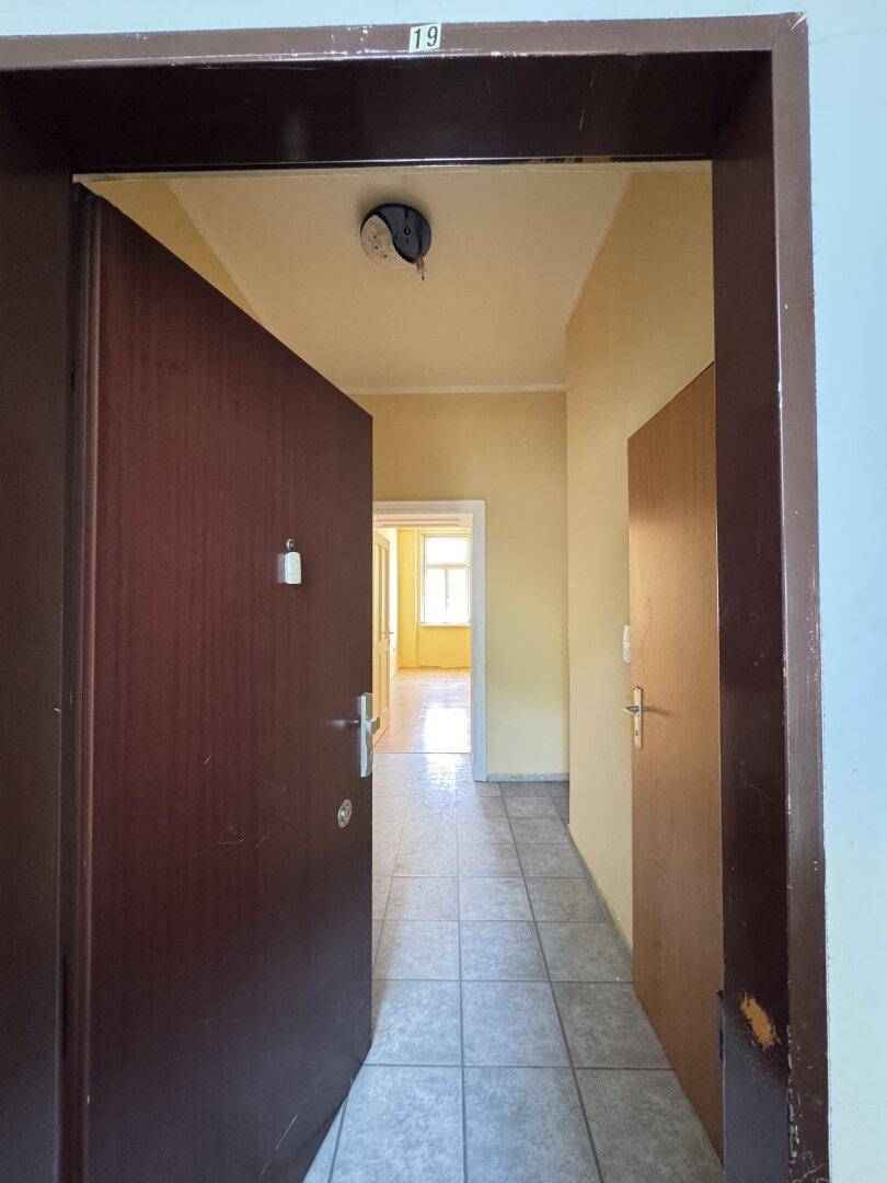 Blick aus der Wohnungstür in den Flur mit Fliesenboden und weiterem Zugang zu den Räumen.