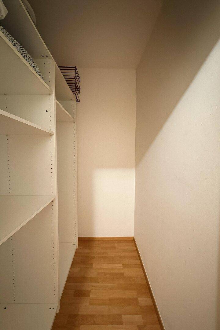 Praktischer Abstellraum mit weißen Regalen und Parkettboden für zusätzlichen Stauraum.