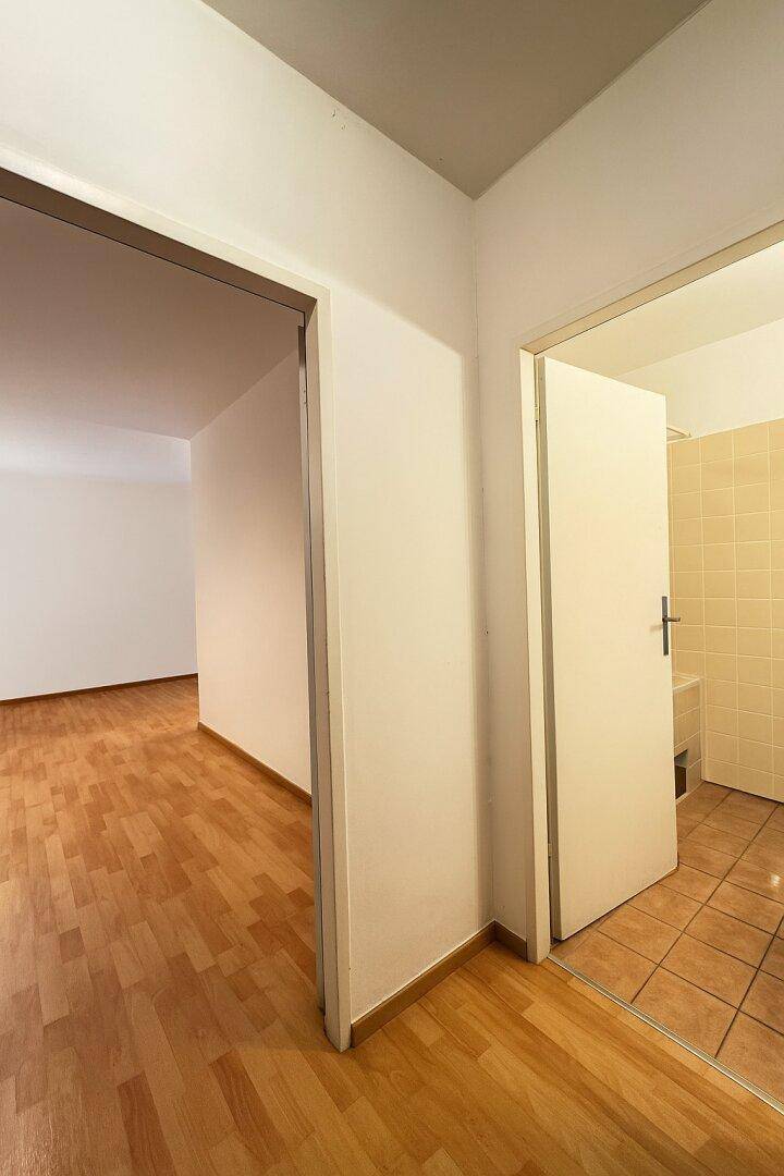 Heller Flur mit Parkettboden und Blick in ein gefliestes Badezimmer.