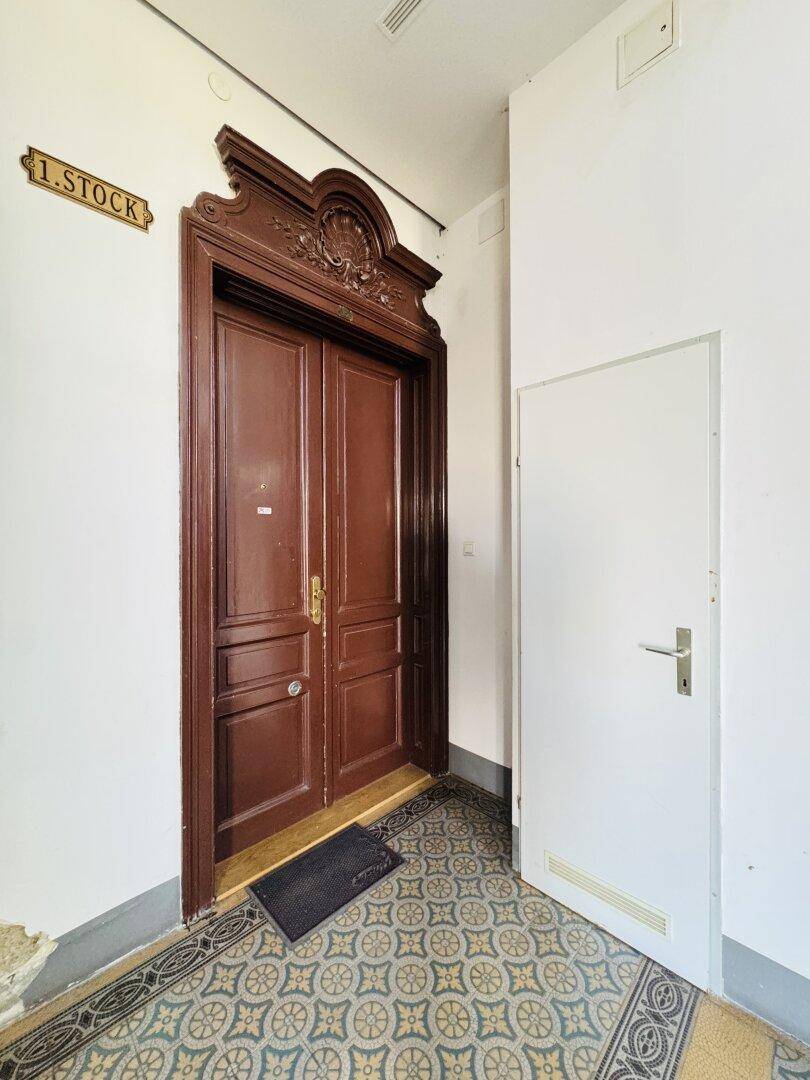 Historische Wohnungstür im ersten Stock mit aufwendigen Holzschnitzereien und traditionellem Design.