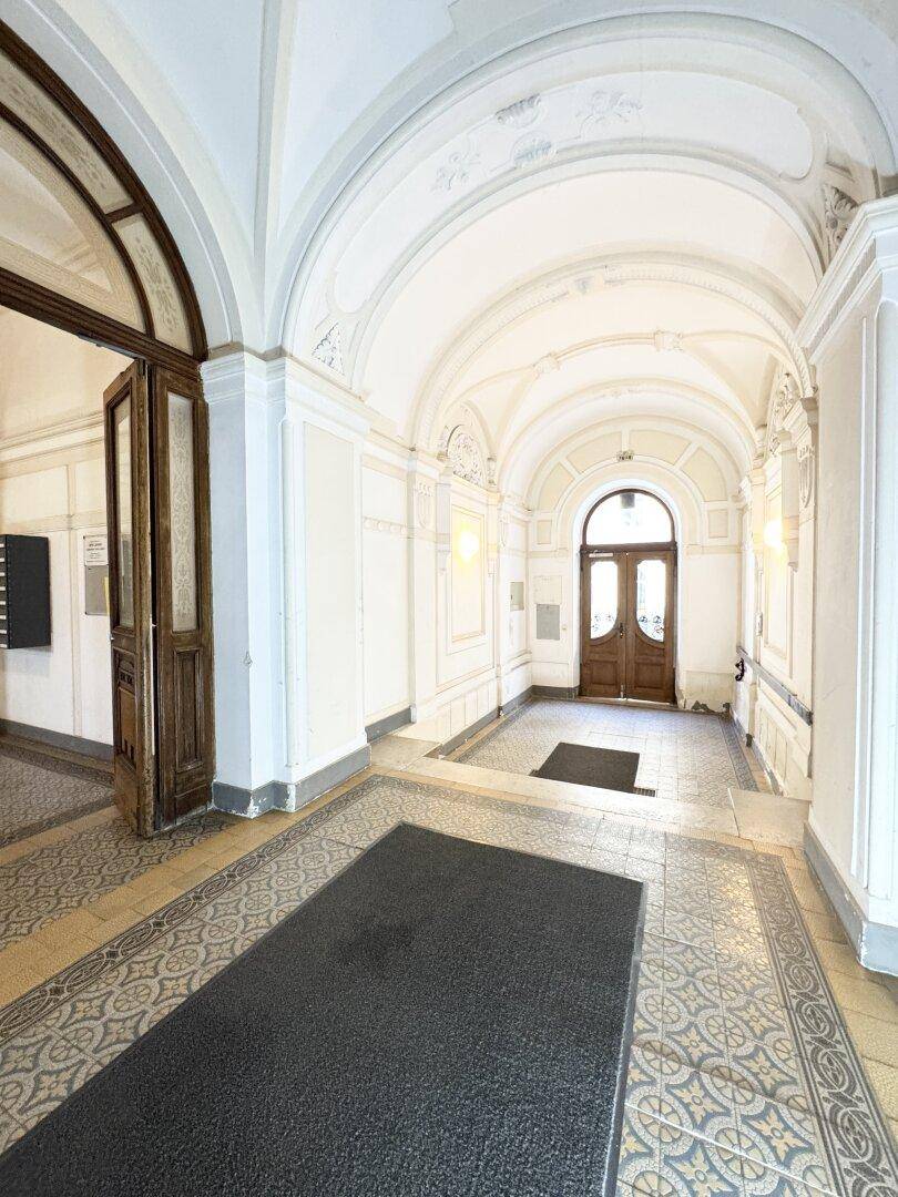 Elegante Eingangshalle mit kunstvollen Stuckverzierungen und historischen Fliesen, die eine prunkvolle Atmosphäre schafft.