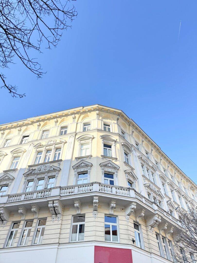 Prachtvolles Eckgebäude mit historischer Architektur und vielen Fenstern unter klarem Himmel.