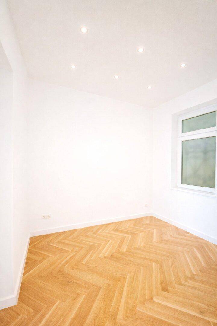 Kleineres, helles Zimmer mit Parkettboden und Einbaustrahlern an der Decke.