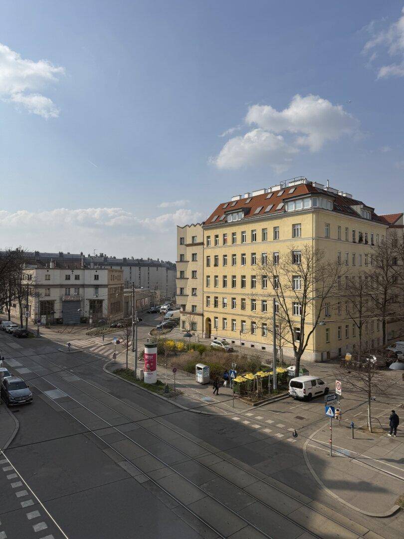 Weitläufiger Blick auf die Stadtstraße mit umliegenden Gebäuden und blauem Himmel.