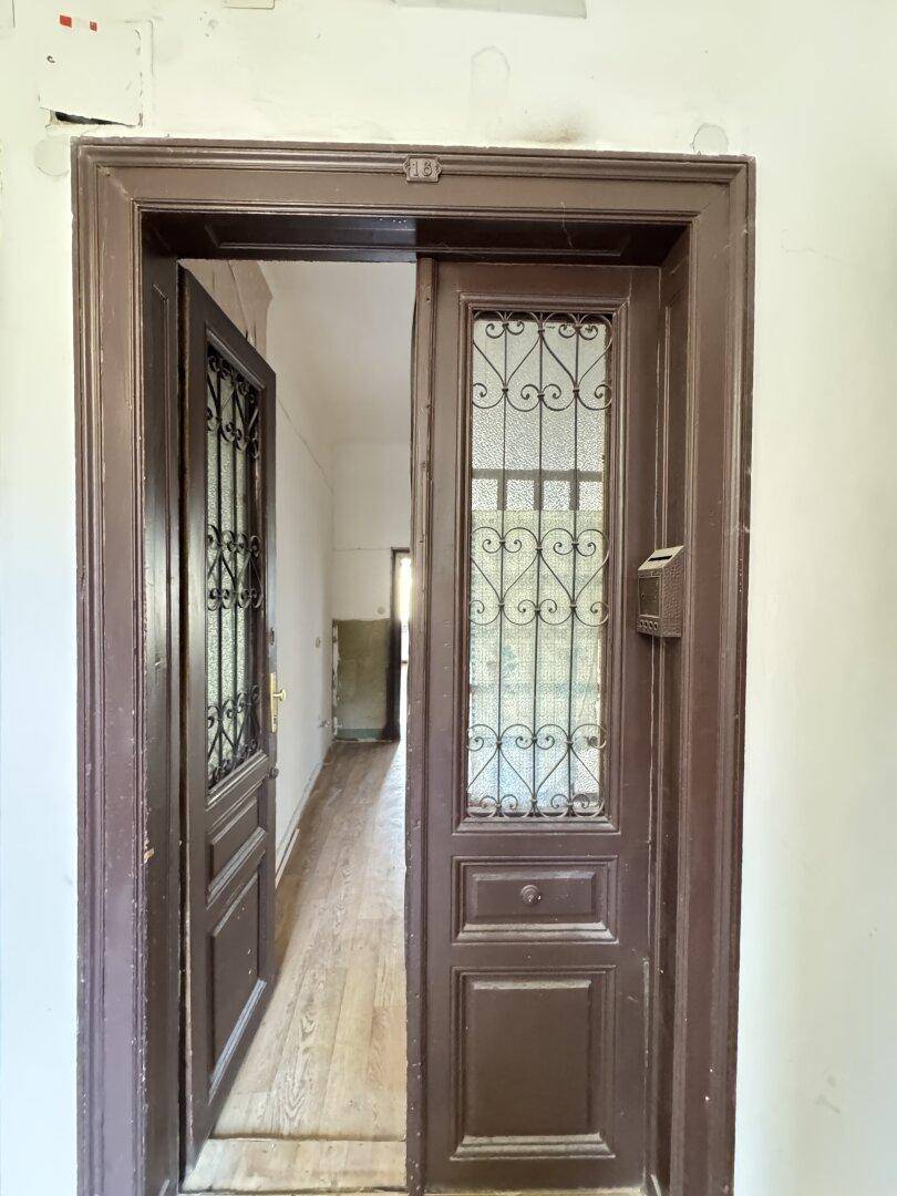 Historische Eingangstür aus Holz mit kunstvollen Glas- und Gitterelementen.