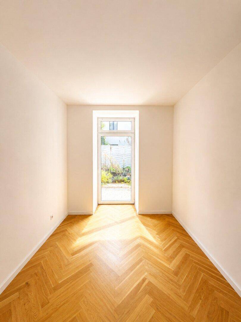 Lichtdurchfluteter Raum mit Fischgrätparkett und direktem Zugang zum Gartenbereich.