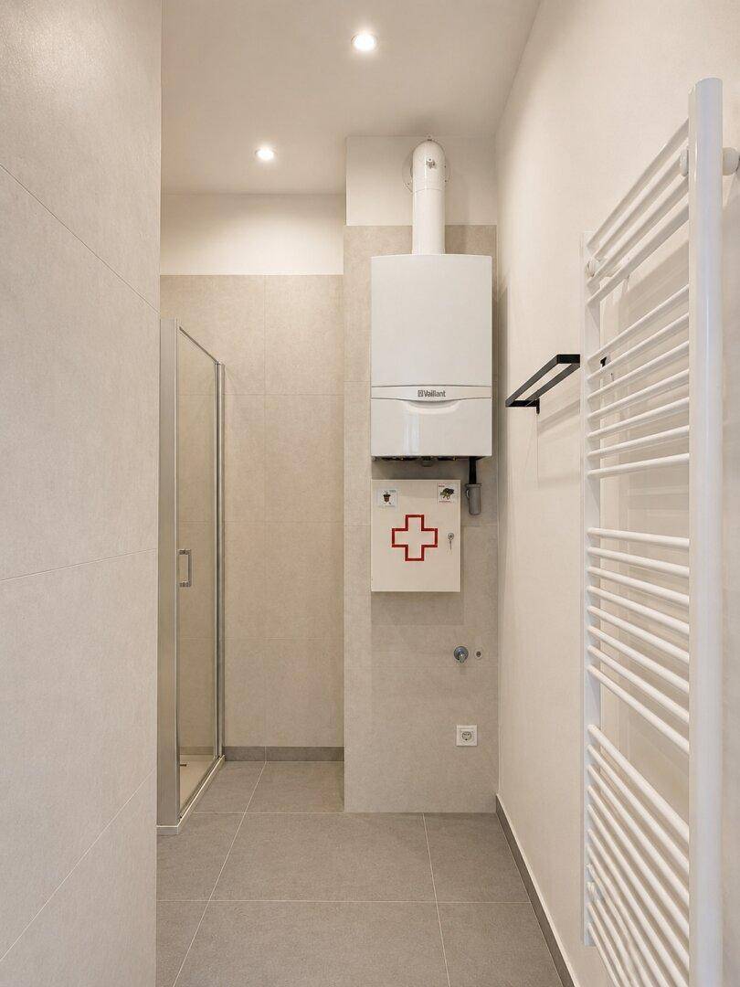 Hauswirtschaftsraum mit Gastherme, Duschkabine und beheiztem Handtuchhalter.