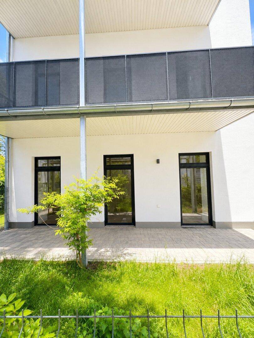 Gepflasterte Terrasse im Erdgeschoss mit Zugang zu den Innenräumen und Grünfläche.