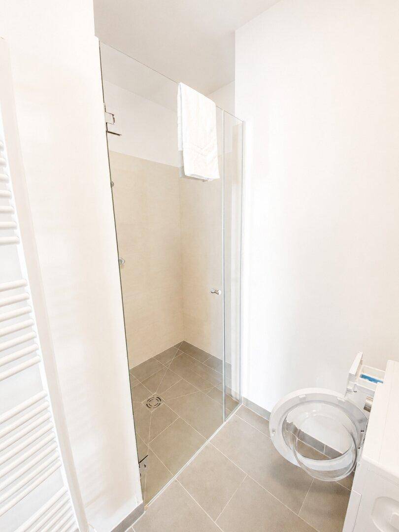 Geräumige, begehbare Dusche mit Glasabtrennung und modernen Fliesen, barrierefrei und elegant.