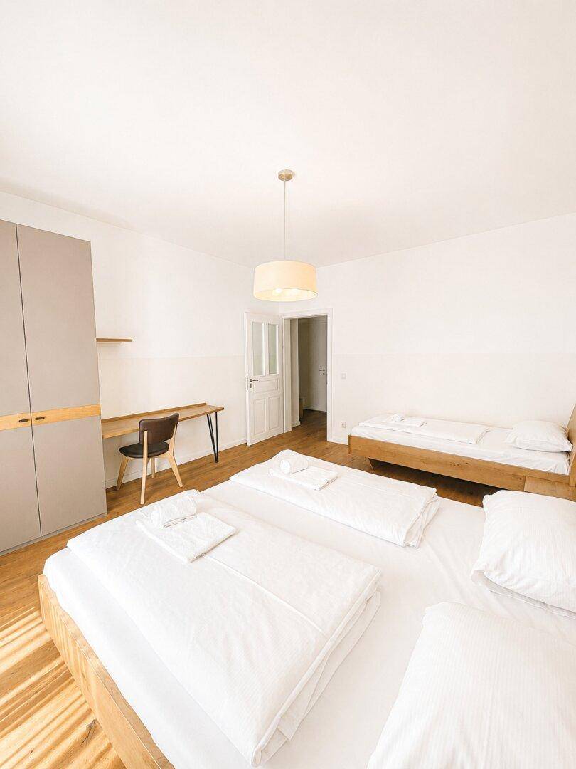 Geräumiges Schlafzimmer mit Doppelbett, Schrank und Schreibtisch, viel natürliches Licht und Stauraum.