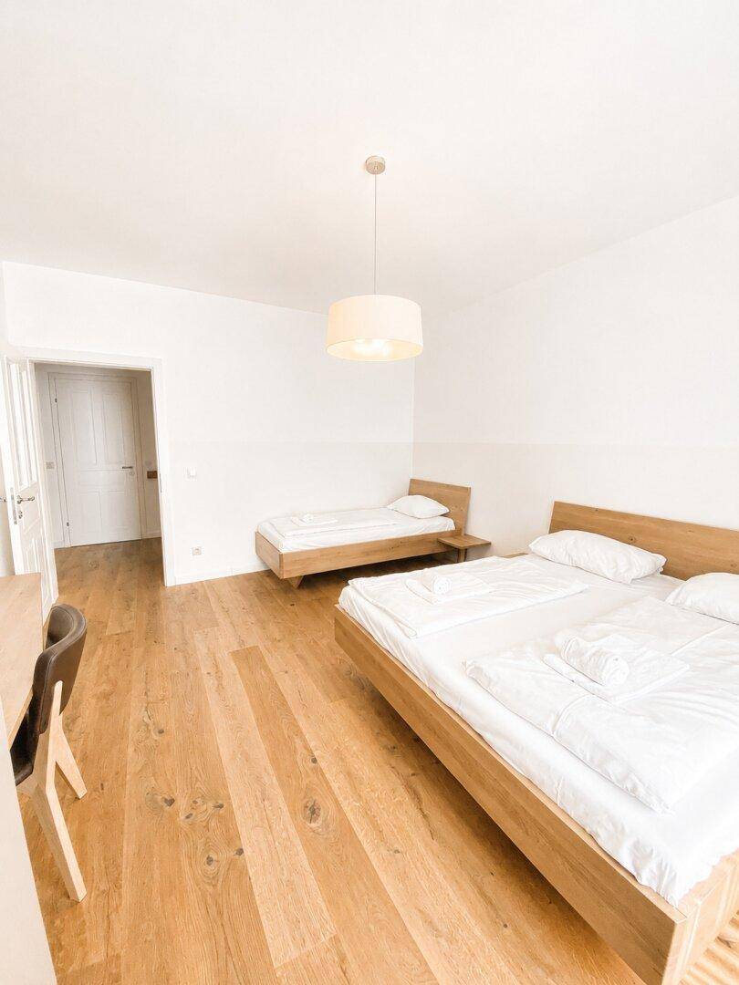 Helles Schlafzimmer mit zwei Betten und Holzboden, ideal für Gäste oder Kinder, mit viel Platz.