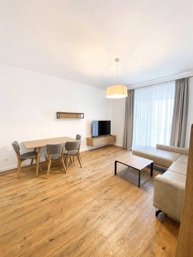 Heller Wohn- und Essbereich mit Holzboden, Sofa und Esstisch, ideal für gesellige Stunden.