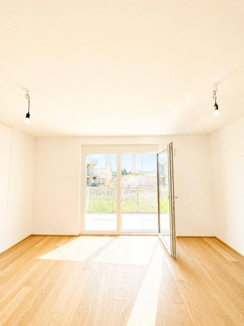 Geräumiges, helles Zimmer mit Parkettboden und großen Fenstern, die sich öffnen lassen.