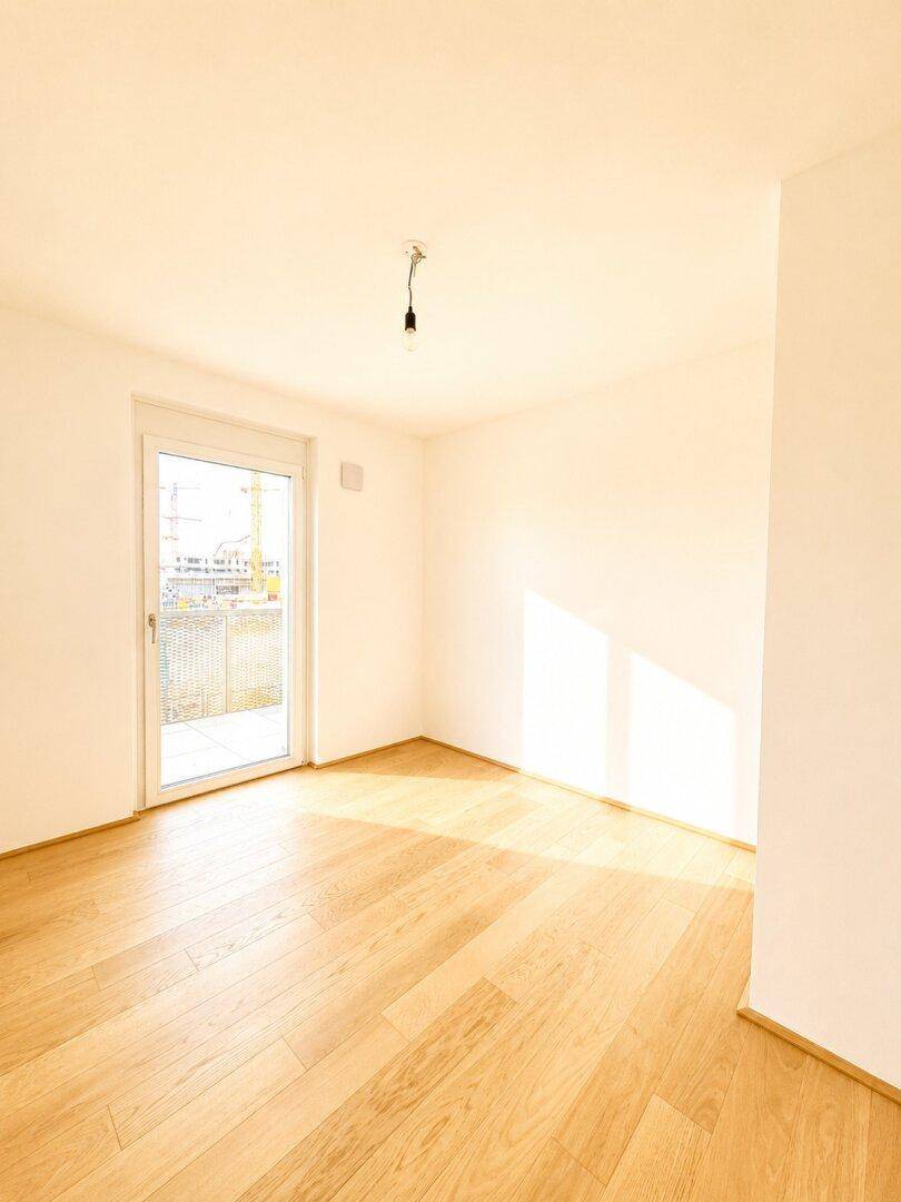Helles Zimmer mit Parkettboden und Zugang zu einem Außenbereich, ideal für ein Schlafzimmer.