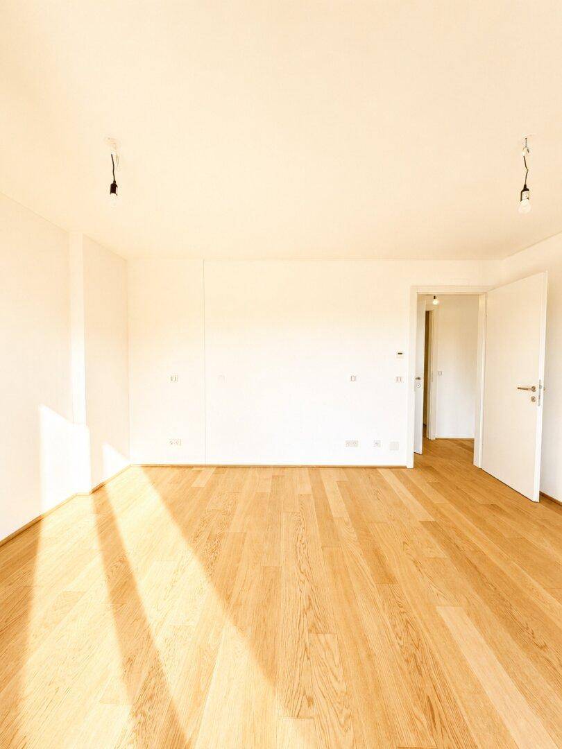 Großzügiger, heller Raum mit Parkettboden und Zugang zu anderen Bereichen der Wohnung.