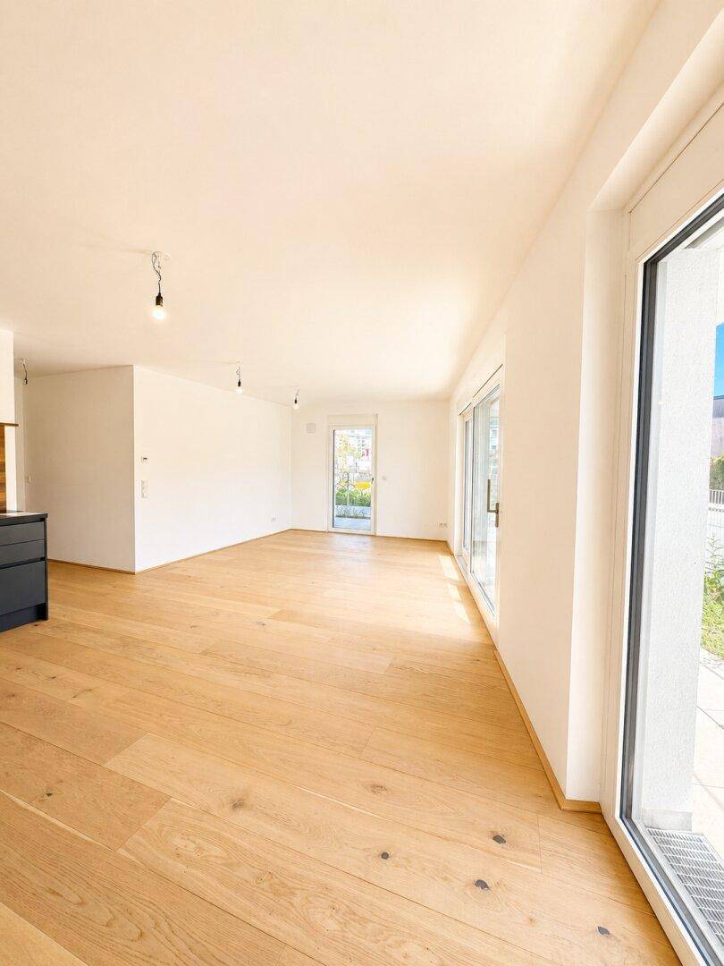 Geräumiges, helles Zimmer mit Holzboden und Zugang zu einem Außenbereich.