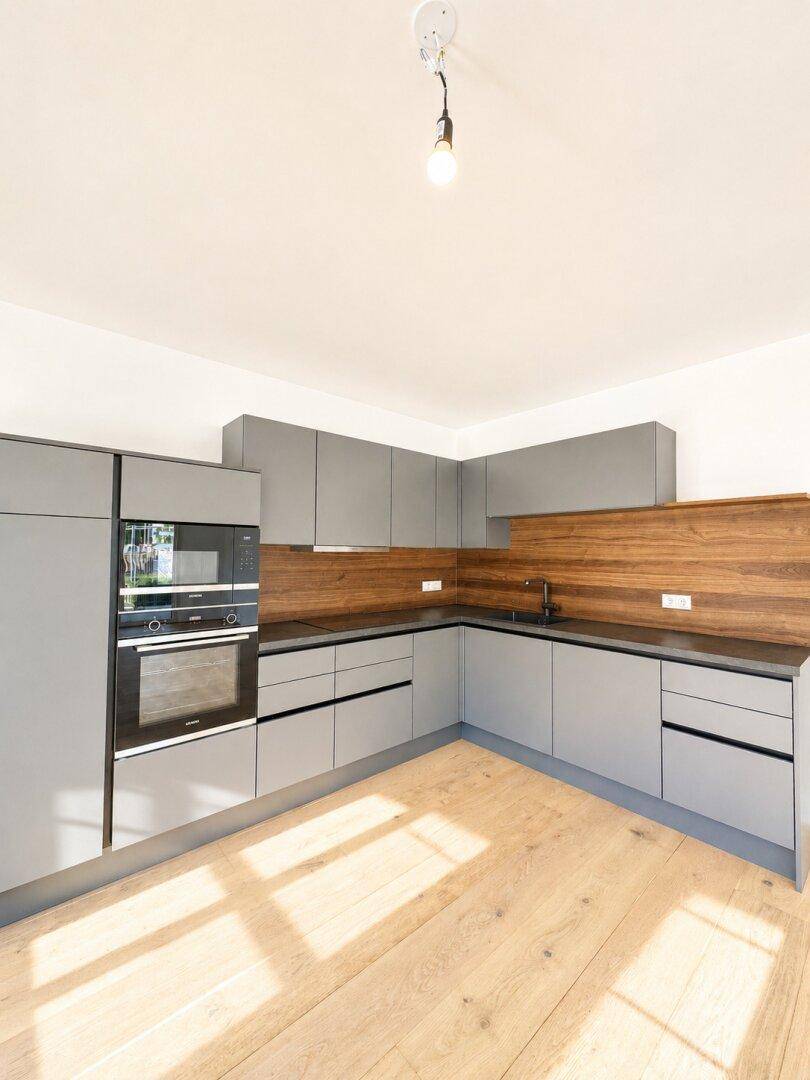 Moderne Einbauküche in Grau mit Holzdetails und integrierten Geräten.