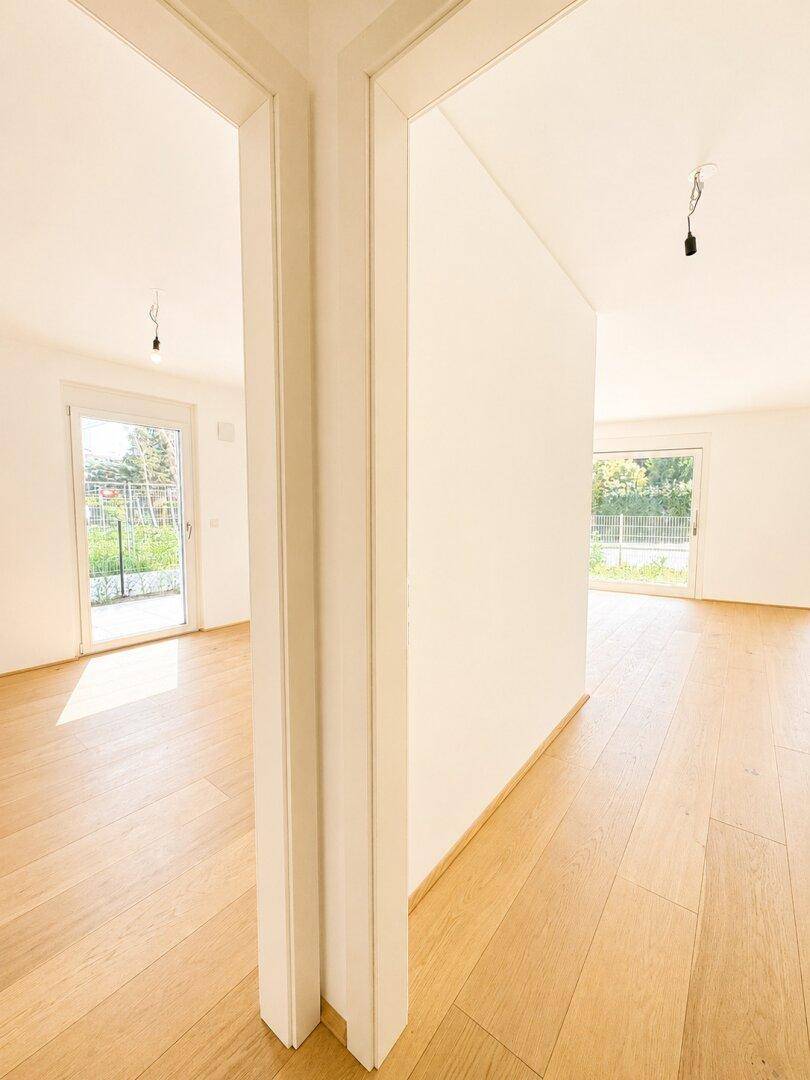 Innenansicht mit einer Trennwand zwischen zwei hellen Räumen mit Holzboden.