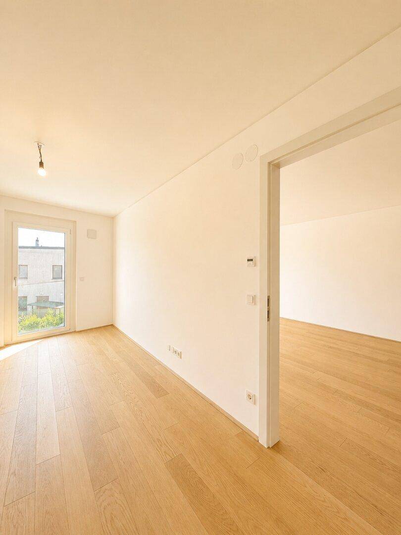 Lichtdurchfluteter Raum mit Holzboden und Fenster, das viel Tageslicht hereinlässt.