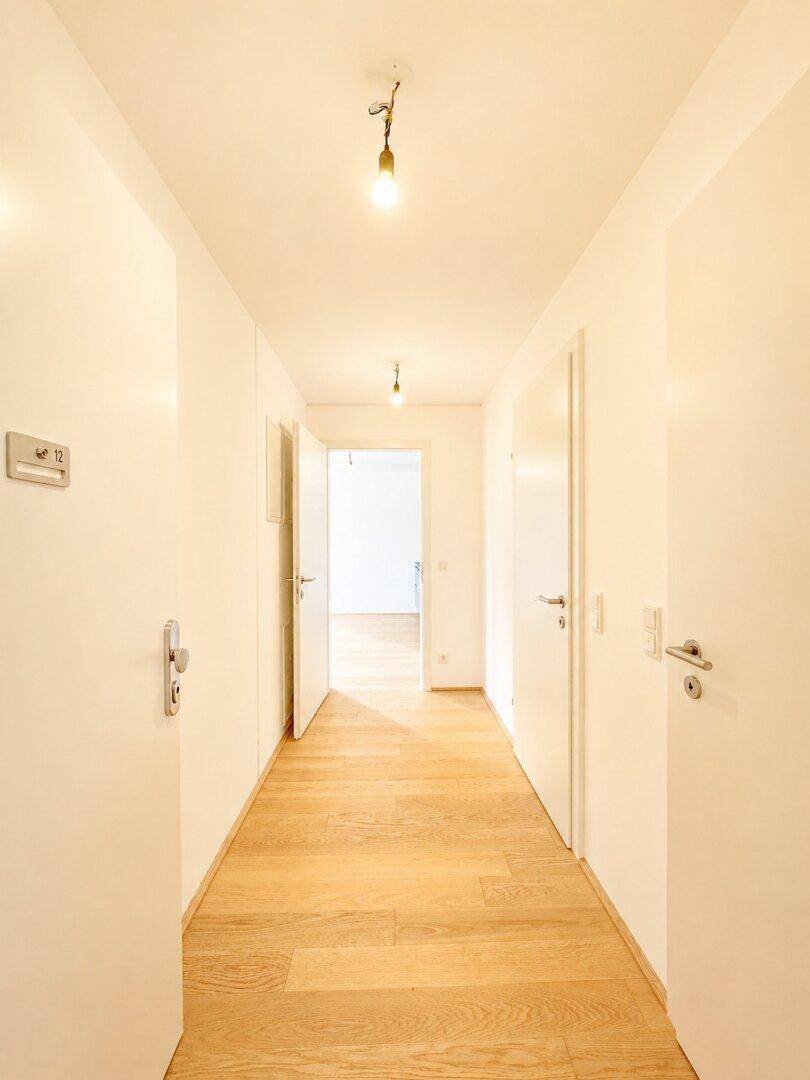 Langer, heller Flur mit Holzboden und mehreren Türen zu angrenzenden Räumen.
