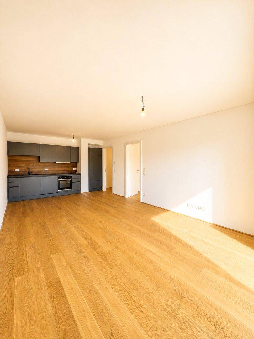 Offener Wohnbereich mit integrierter Küche, Holzboden und viel natürlichem Licht.