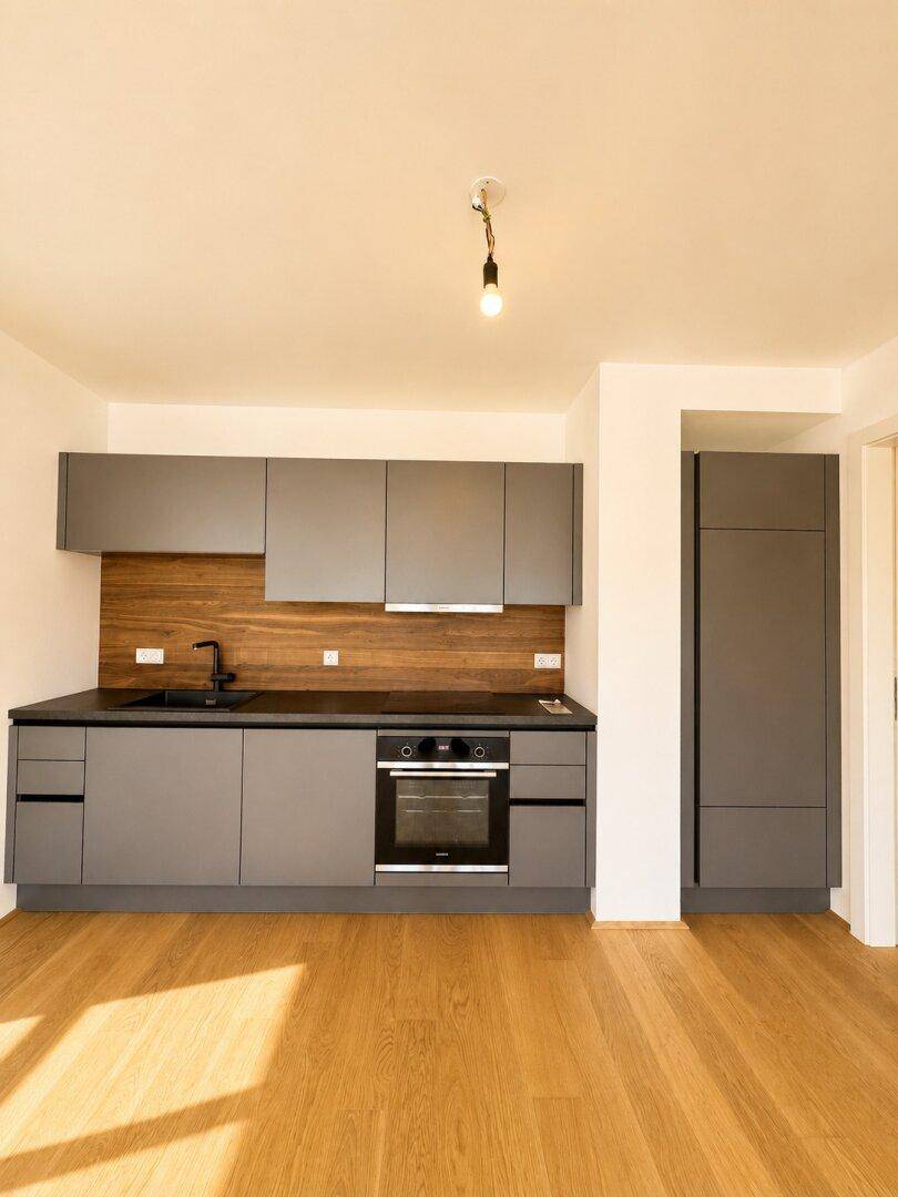 Moderne Einbauküche in Grau mit Holzrückwand und integriertem Backofen.